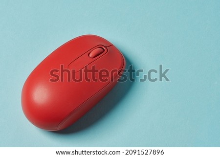Red wireless mouse on blue background. Computer mouse.