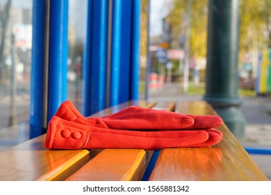 Red Women's Gloves Forgotten On A Bench Or At A Bus Stop On A Warm Sunny Day. Warehouse Or Lost And Found, Lost Things.