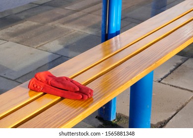 Red Women's Gloves Forgotten On A Bench Or At A Bus Stop On A Warm Sunny Day. Warehouse Or Lost And Found, Lost Things.