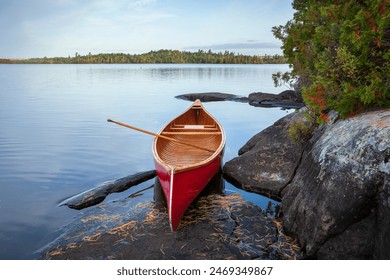 Red wood canoe on rocky shore of a Boundary Waters lake in morning light during autumn - Powered by Shutterstock