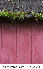 red wood wall with overgrown gutter