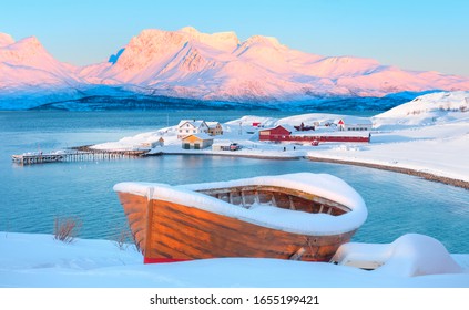 Red wooden boat covered with layers of snow - Beautiful winter landscape with snow covered red house - Tromso, Norway - Powered by Shutterstock