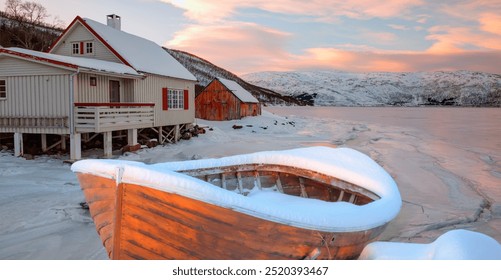 Red wooden boat covered with layers of snow - Beautiful winter landscape with snow covered red house - Tromso, Norway - Powered by Shutterstock