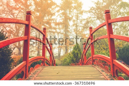 Red wooden bridge in soft light  

Wooden bridge with the red handrails in a japanese garden, against a background of autumnal trees.