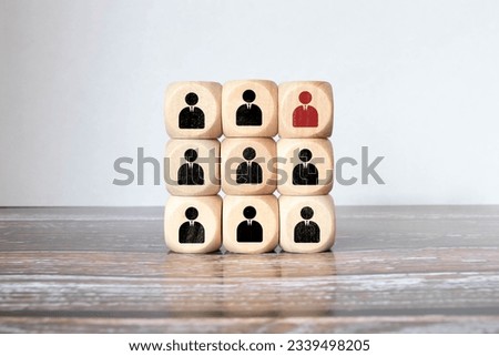 Red wooden cube with person icon stand out from the crowd on blue background. Dissenting opinion, divergent views and different concepts