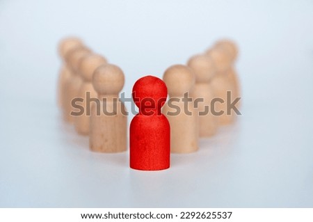 Red wooden figure representing a leader leading other figure. Leadership concept