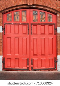 Red Wooden Gates Of Vintage Fire Station. On Red Brick Wall