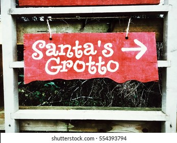 A Red Wooden Sign For A Santa's Grotto