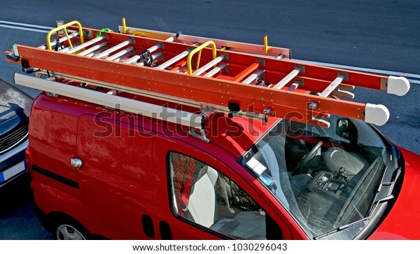 Red work\
van with ladders and equipment on the\
roof.