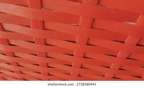 Red woven plastic texture background, abstract pattern of intertwined synthetic fibers.