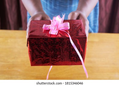 red wrapped gift box given to loved ones. giving of gift 