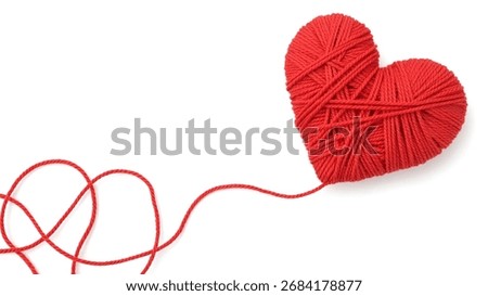 A red yarn heart with a string trailing off to the left.