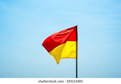 Red And Yellow Beach Safety Flag Against Pale Sky, Fluttering In Wind.