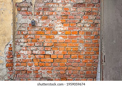 Red Yellow Gray Wall Background. Old Damaged Red Brick Wall With Yellow Plaster. Switch On The Wall. Brushed Metal Door In The Brick Wall. 