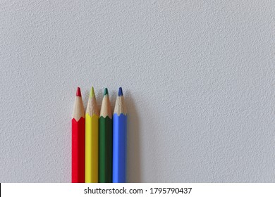 Red, Yellow, Green And Blue Pencils Are Standing In Front Of A White Wall