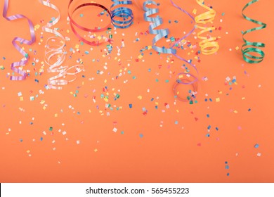 Red, Yellow And Green Heart And Circle Confetti On A ORANGE Background.