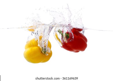 Red and yellow sweet pepper thrown into a bowl of water