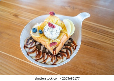 Redberry on top of chocolate chip ice cream. on the honey toast Along with various fruits such as blueberries, bananas, put on the brown wooden tableware in the bakery. - Powered by Shutterstock