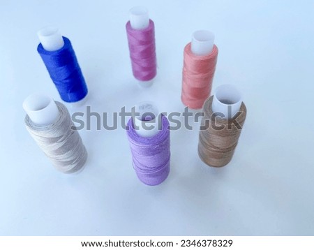 Red-colored reels of thread stand on a white background.