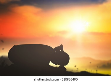 Redemption concept: Silhouette christian woman kneeling and praying over autumn sunset background