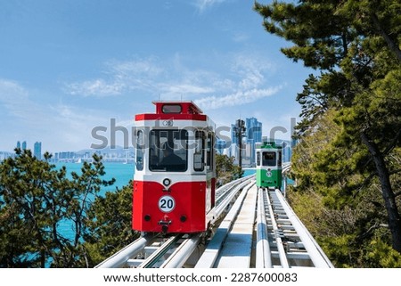 Red-green sky capsule train running on seaside railway tracks in Busan, Korea. It is a destination for tourists to sit and enjoy the view.