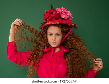 Redhair Beautiful Girl With Curly Afro Curls In Bright Pink Dress On Green Background. Curly Hair Care, Freckle Cream, Teen Book Cover. Close-up Fashion Photo. Art Hat Flowers