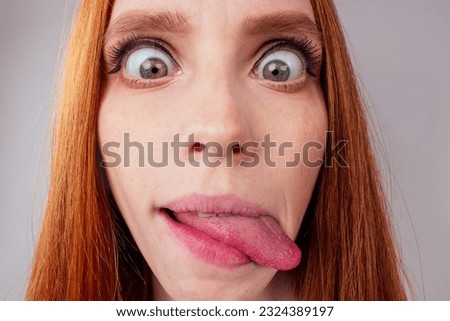 redhair ginger woman demonstrating tongue and making stupid face with crossed eyes