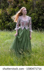 Red-haired 18th Century Woman Wearing An Embroidered Bodice And Wandering In Long Grass