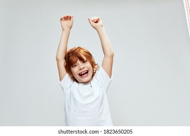 Red-haired boy with raised hands up smile cropped view white t-shirt 
