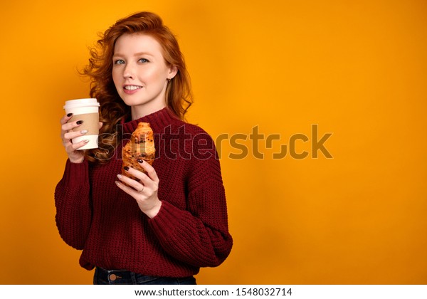 黄色い背景に赤い毛の巻き毛の少女が微笑み 紙コップとクロワッサンを持つ の写真素材 今すぐ編集