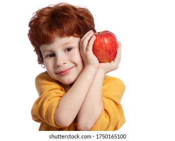 A red-haired European boy holds a red Apple in his hands. Vitamins and fruits, healthy food. Portrait of a happy beautiful child on a white background.