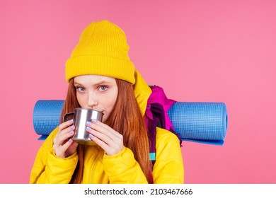 Redhaired Ginger Woman Wrapped Up Sleeping Bag And Drinking Hot Tea In Studio Pink Background