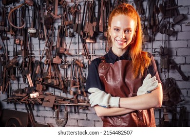 redhaired ginger young european feminist woman wearing leather apron working blacksmith workshop.small business strong and independent concept - Powered by Shutterstock