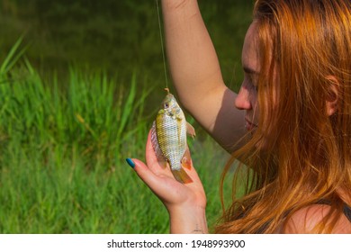 Red-haired girl holding fish by hook - Powered by Shutterstock