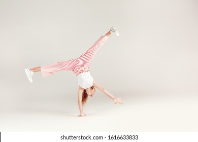 Red-haired girl isolated on grey background inclusive beauty standing on hands doing cartwheel smiling happy