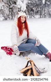 A Red-haired Girl Is Roasting Marshmallows On An Open Fire In Winter