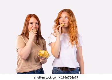 Red-haired girls eat potato chips. A quick snack on a white background with empty side space for text or advertising. High quality photo