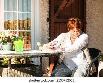 red-haired grandmother laughing on the porch of her house on a spring day