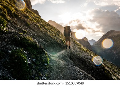 Red-haired Hiker in the Swiss Alps with Male backpacker enjoying views in Val Müstair, Switzerland. Concept: go further and beyond, hero shot, above and beyond
