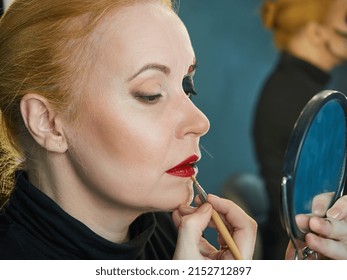 Red-haired Mature Woman Doing Make-up, Applying Red Lipstick On Her Lips