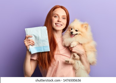 red-haired pretty positive girl controlling pissing process of her pet. close up portrait isolated blue background
