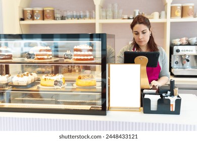 red-haired waitress at the counter of her cafeteria pastry shop enters amount in her computer to charge for homemade cake. - Powered by Shutterstock