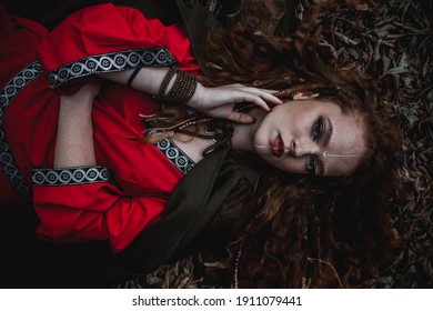 Red-haired Woman In A Red Dress In A Historical Celtic Costume In The Autumn Forest