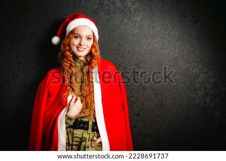 A red-haired woman in a Santa Claus costume and a red hat. Portrait of a happy girl in a military army uniform on a black dark background. Concept of Christmas or New Year. Stock photo © 