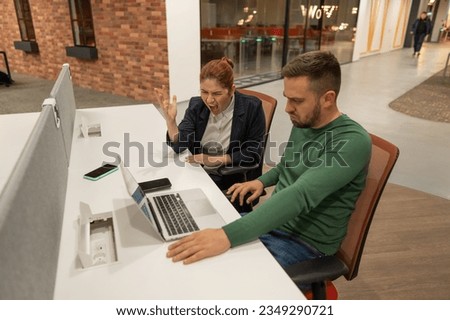 A red-haired woman swears at a male subordinate. Colleagues discussing work. 