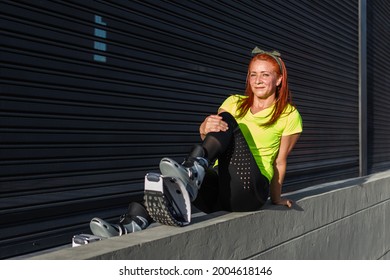 Red-haired Woman Wearing Sportswear And Kangoo Jumps Boots Resting After A Physical Exercise Routine In Front Of A Metal Rolling Door