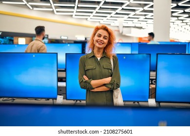 Red-haired Young Woman Chooses Plasma In Store Of Household Appliances, Electronics And Gadgets. Buying New TV, Sale Day.