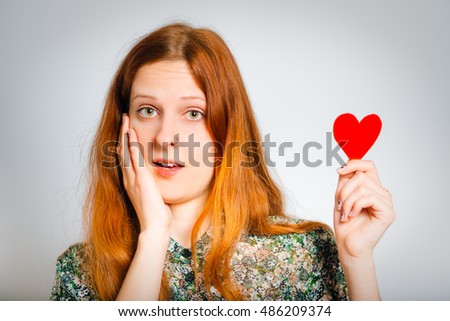 redhaired young woman holding a paper heart, isolated close-up