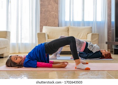 Redhead adult woman and brunette little girl wearing sports clothes doing fitness on mats indoors. Health concept - Shutterstock ID 1702643503