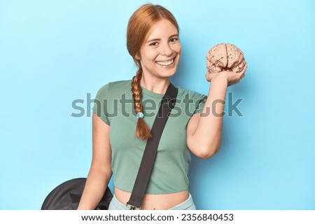 Redhead athlete holding brain model, showcasing sport's cognitive benefits